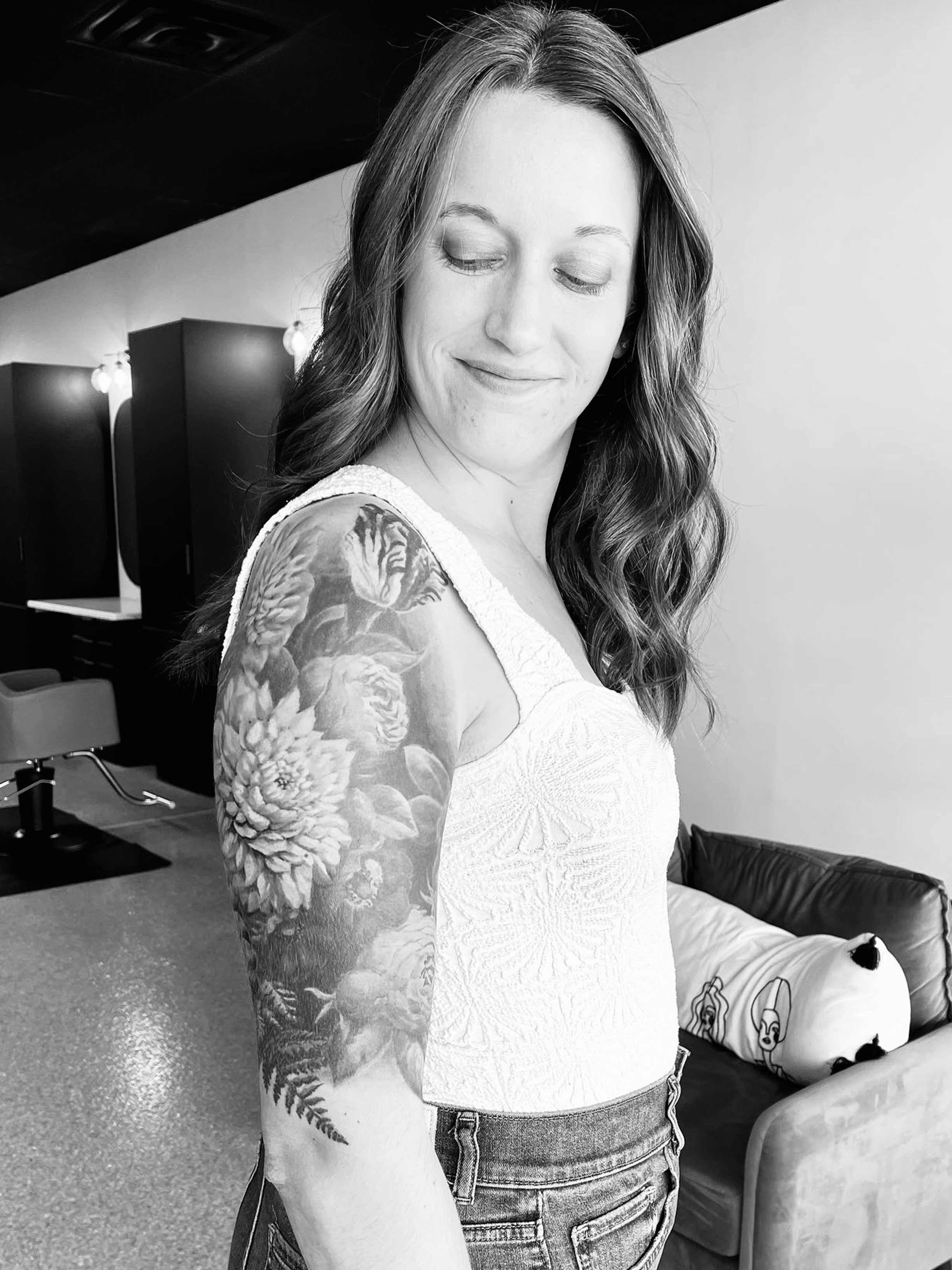 Katy Williams looking down over right arm, highlighting upper half sleeve floral tattoo